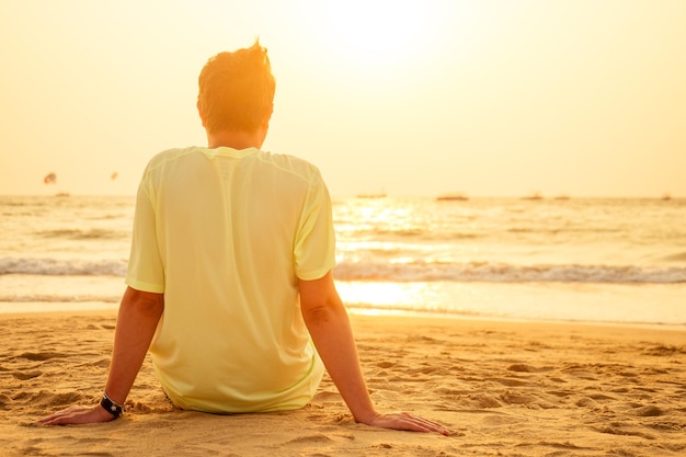 Young man on the beach alone looking at sunset