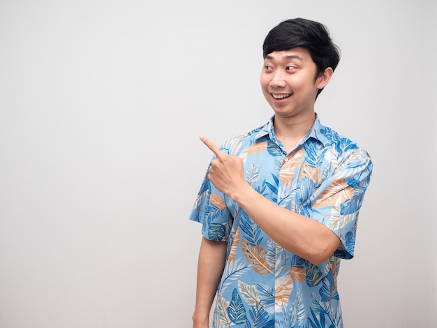 Молодой человек в пляжной рубашке улыбается, указывая пальцем на пространство для копирования