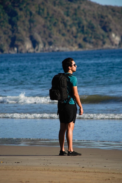 Foto giovane sulla spiaggia con il suo cane e la borsa fotografica