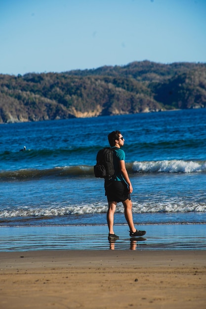 Photo young man in the beach whit his dog and photography bag