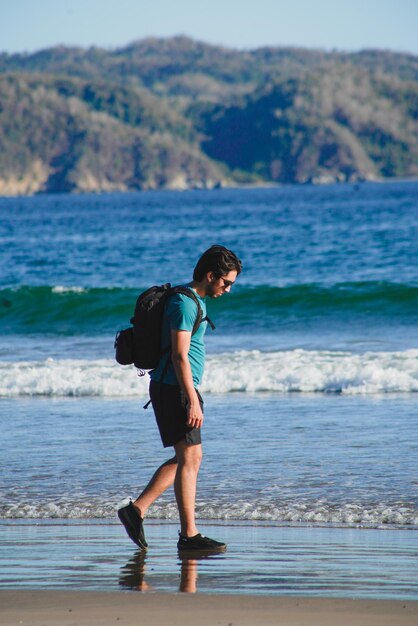 Foto giovane sulla spiaggia con il suo cane e la borsa fotografica