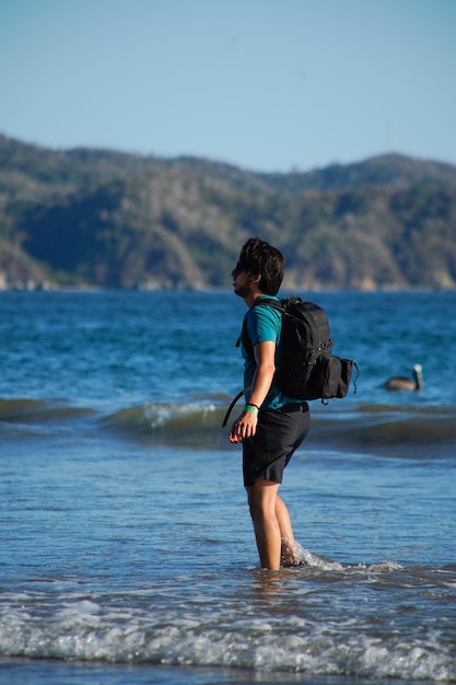 Foto giovane sulla spiaggia con il suo cane e la borsa fotografica