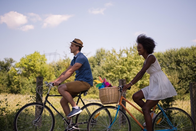 a young man and a beautiful African American girl enjoying a bike ride in nature on a sunny summer day