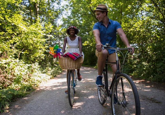 晴れた夏の日に自然の中で自転車に乗ることを楽しむ若い男と美しいアフリカ系アメリカ人の女の子