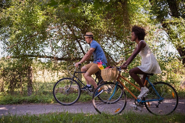 a young man and a beautiful African American girl enjoying a bike ride in nature on a sunny summer day