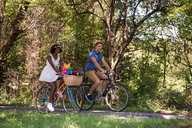 晴れた夏の日に自然の中で自転車に乗ることを楽しむ若い男と美しいアフリカ系アメリカ人の女の子