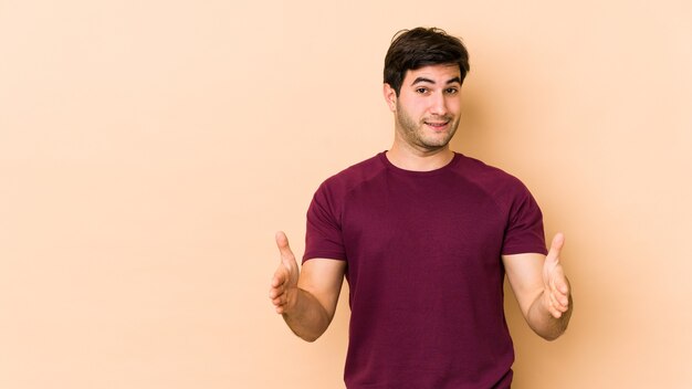 Young man on beige holding something with both hands, product presentation.