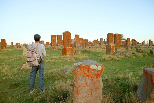 Young man being impressed by the world biggest Khachkars field at Noratus medieval cemetery Armenia