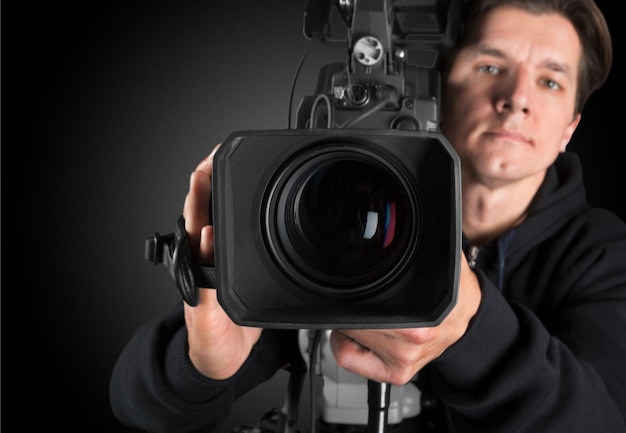 Young man in black clothes holding big video camera