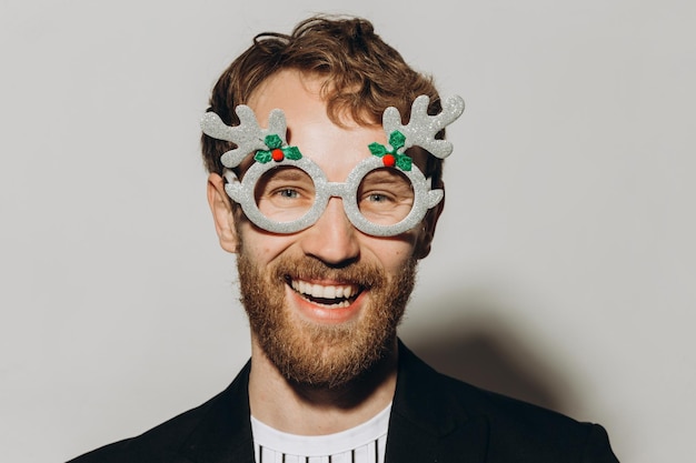 Young man in black jacket with party glasses on color background