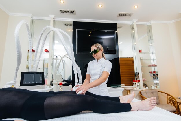 A young man in a black suit, undergoing a cosmetic LPG massage, close-up. Cosmetic procedure in a medical center. Anti-cellulite treatments, rejuvenation and Hydration. Cosmetology. Selective focus.