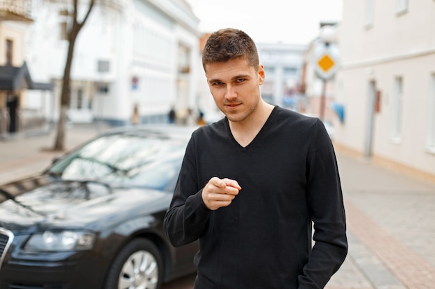 Il giovane in una maglietta nera punta il dito sulla strada