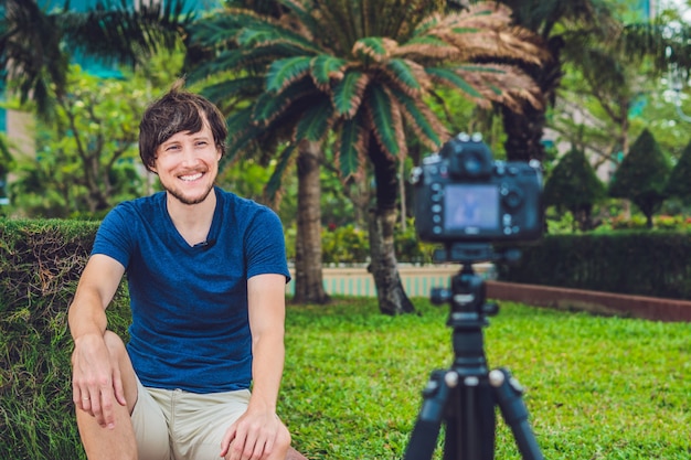 Young man blogger records video in front of the camera in the park