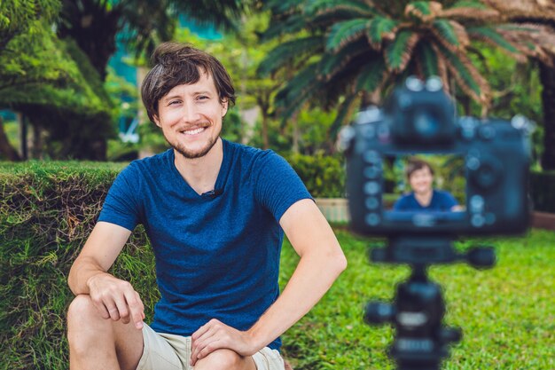Young man blogger records video in front of the camera in the park