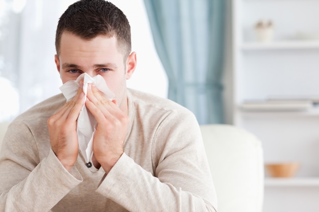 Young man blowing his nose