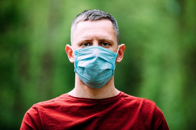 Young man in blue face mask in the forest. breathing of fresh air during pandemic.