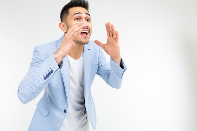 Young man in a blue jacket shouting news on a white background with copy space