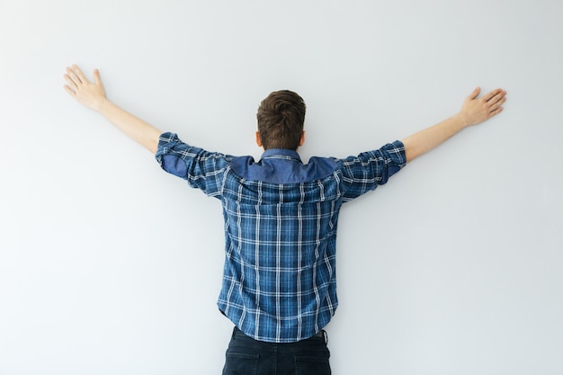 A young man in a blue shirt is facing the wall. depression, problems and stress