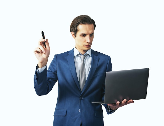 Young man in blue suit going to write with pen and laptop in hands isolated on white background