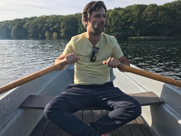 Young man in boat on lake against sky