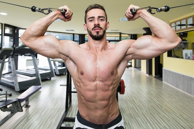 Young Man Bodybuilder Is Working On His Biceps With Cables In A Gym