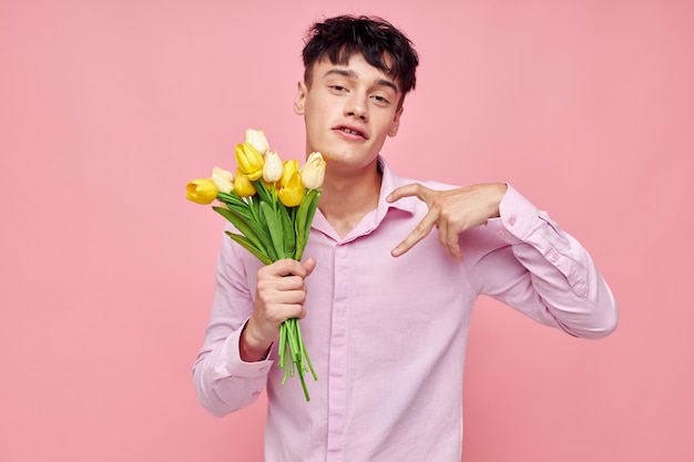 Молодой человек букет желтых цветов романтика позирует на модном розовом фоне без изменений