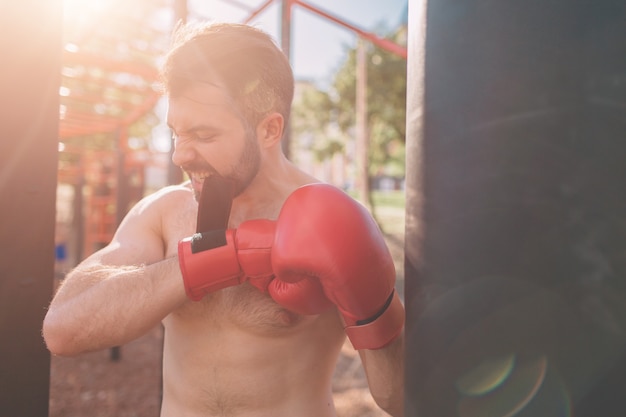 写真 若い男ボクシングトレーニングボクサーエクササイズアスレチックボクシングコンセプトボクサーサンドバッグで手をパンチ