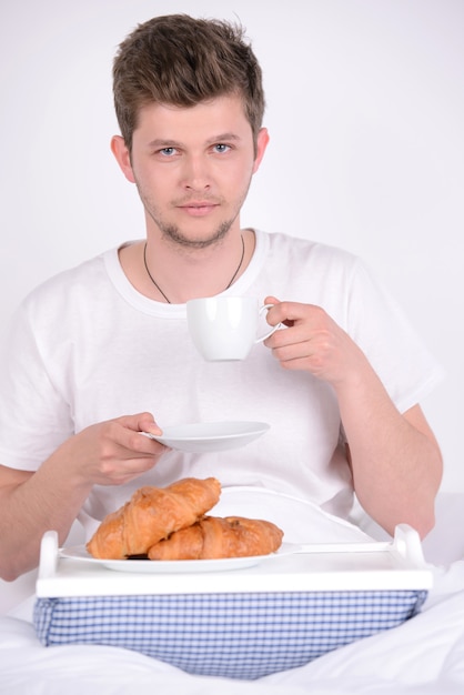 朝食を自宅のベッドで若い男。