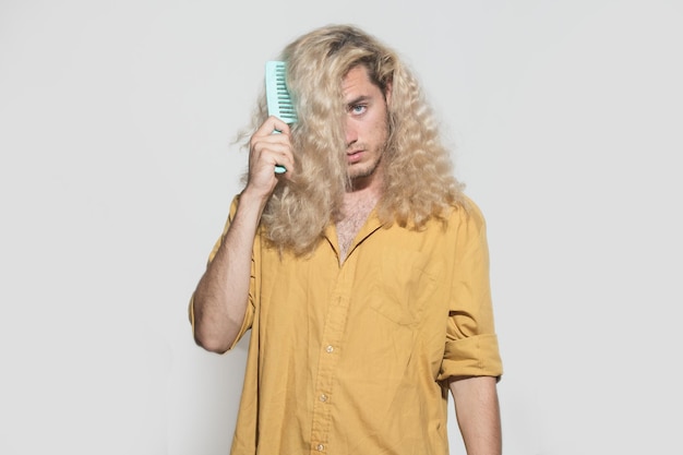 Young man brushing curly blonde hair with comb handsome young blonde man combing hair man with blond