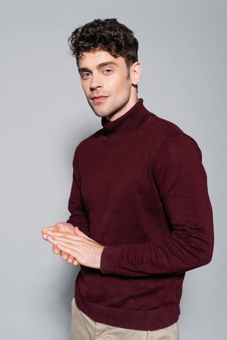 Photo young man in burgundy jumper posing isolated on grey