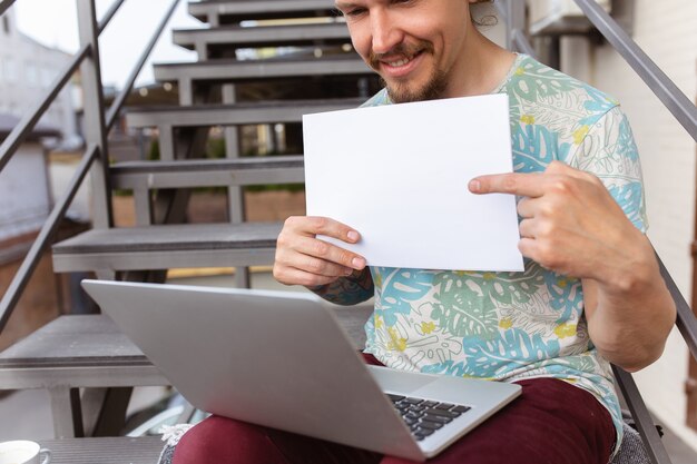 Young man, businessman looking for job using laptop outdoors,