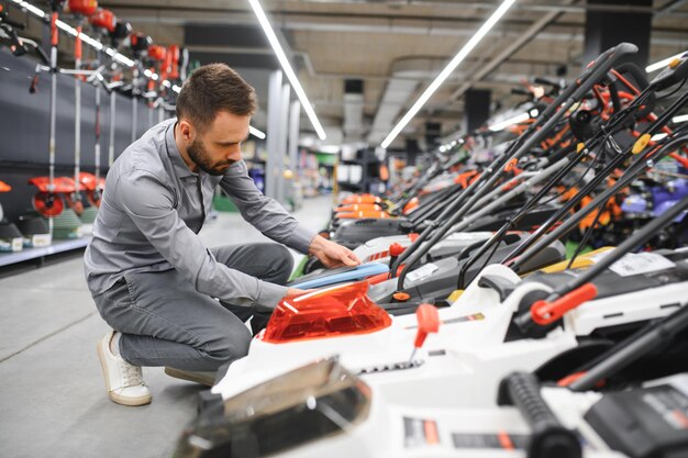 Young man buys a new lawnmower in a garden supplies store