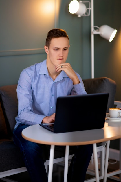 ラップトップに取り組んでいるカフェで若い男