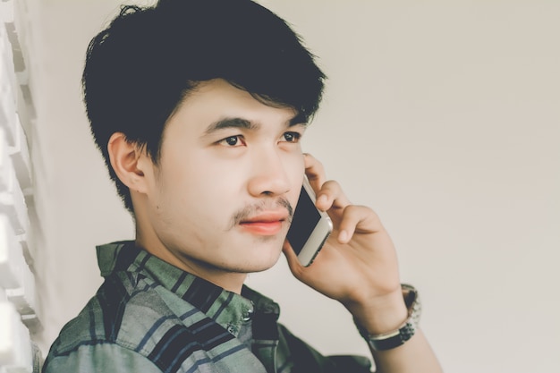 Young man calling with cell telephone while alone in coffee shop during free time.