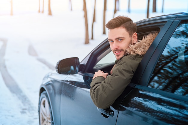 young man in car winter road