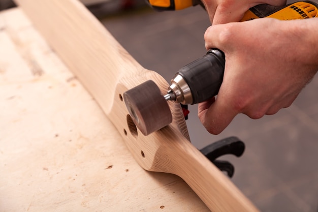 young man carpenter equals polishes wooden board