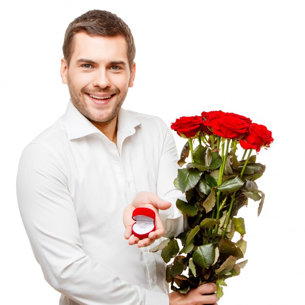 Young man carries heart shaped box and flowers