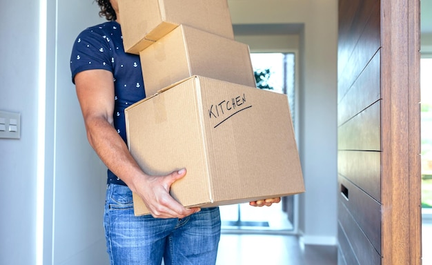 Young man carrying moving in cardboard boxes