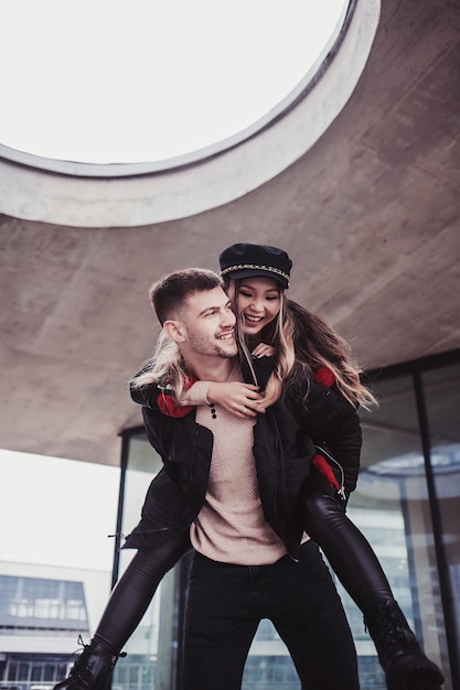 Young man carrying young woman on his back. Happy couple outdoor having fun piggyback