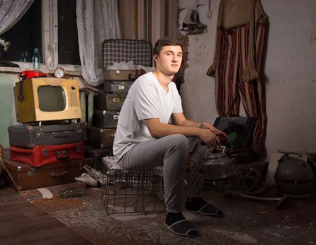 Young Man in Casual Outfit Sitting at the Junk Room Looking at Camera.