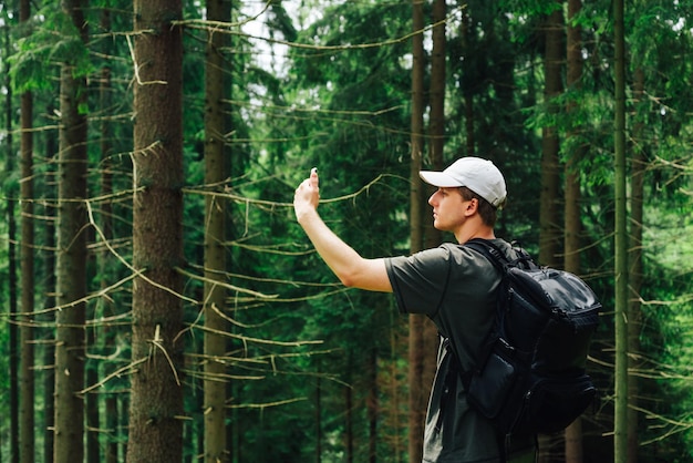 A young man catches a cellular network on a smartphone while walking in the mountains