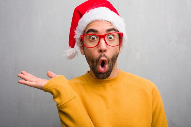 Young man celebrating christmas day holding gifts holding something on palm hand