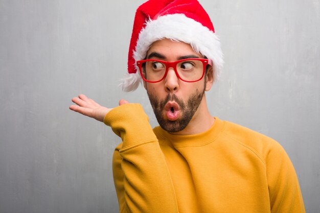 Young man celebrating christmas day holding gifts holding something with hand