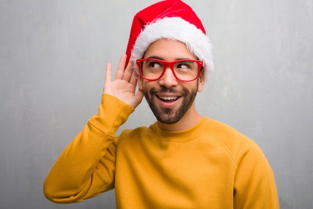 Photo young man celebrating christmas day holding gifts try to listening a gossip