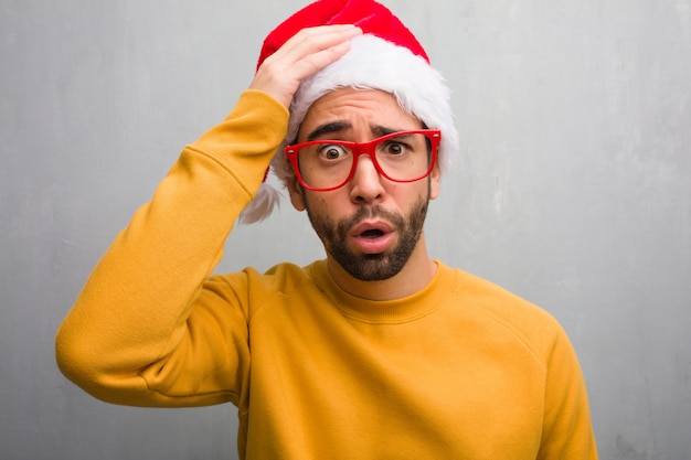 Young man celebrating christmas day holding gifts worried and overwhelmed