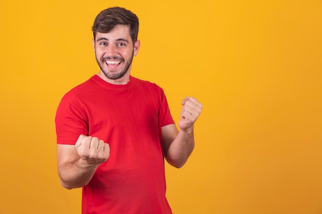 Young man celebrating victory over yellow background