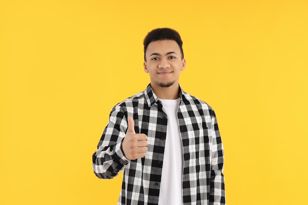 Young man in checkered shirt on yellow background