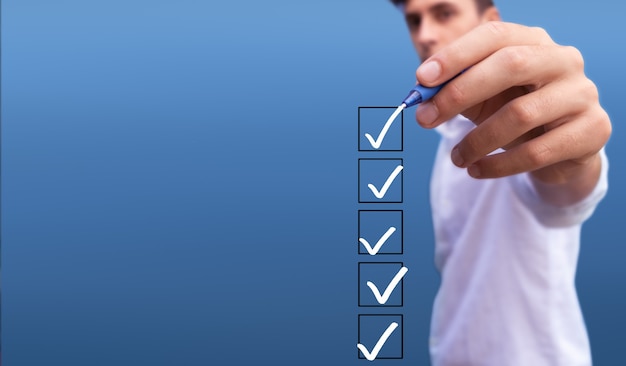 Photo young man checking 5 boxes with list of options on blue background