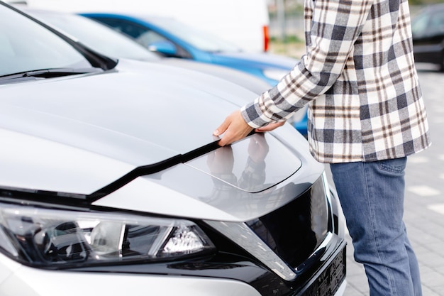 Young man checking under the hood of his car to figure out what the problem is