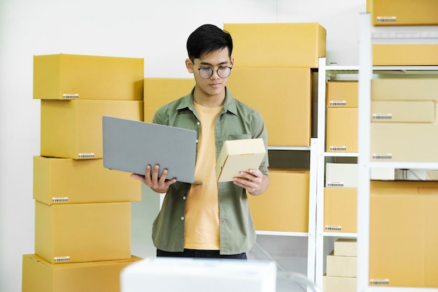 Young man checking parcel address using laptop